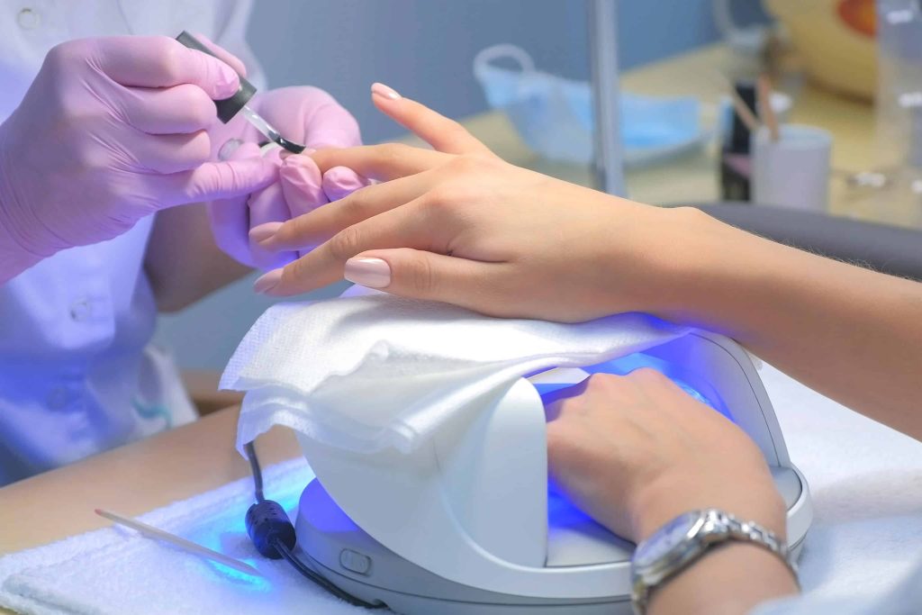 Shellac manicure being cured under a UV lamp during a professional nail treatment