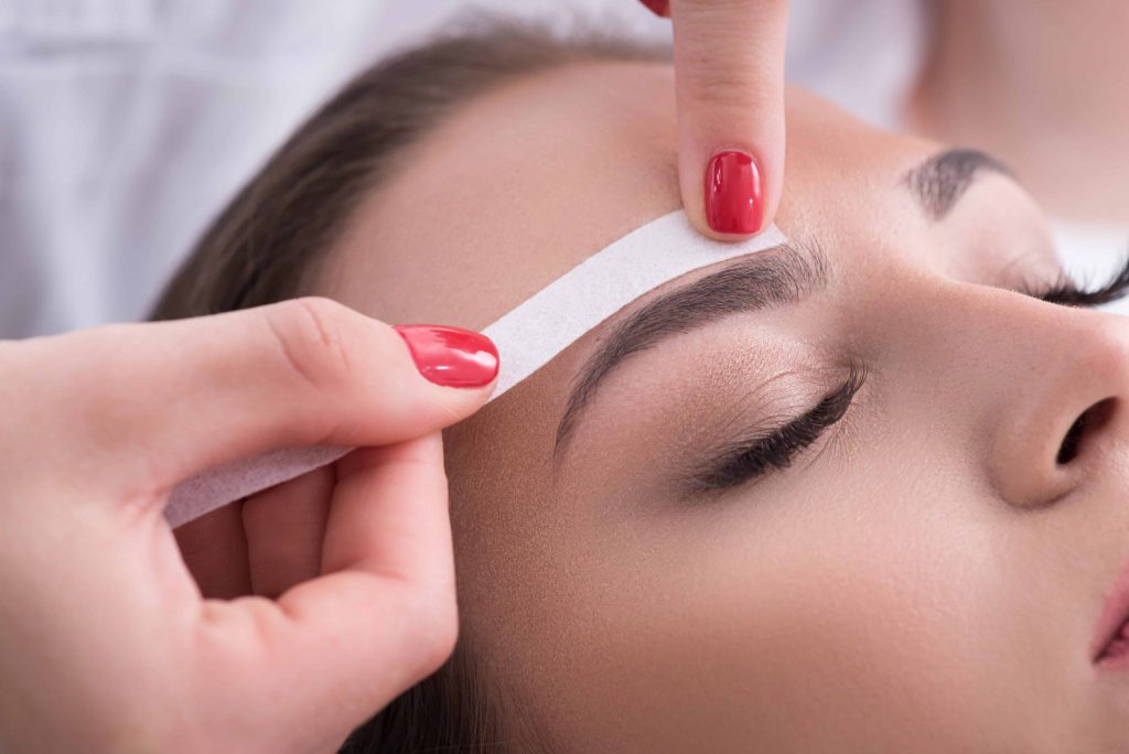 woman waxing eyebrow in a professional beauty bar